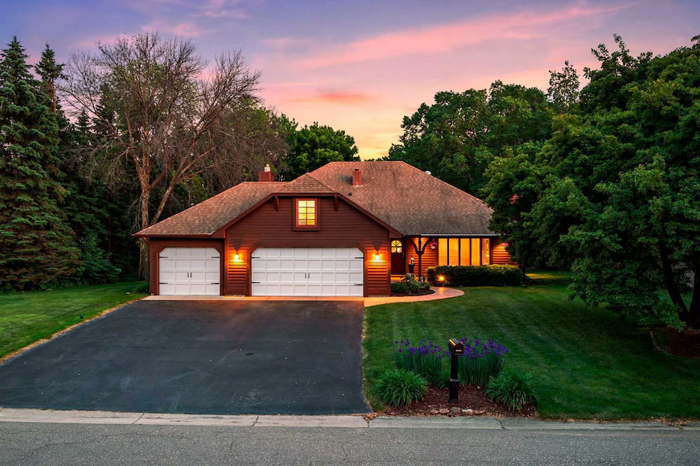 A twilight view of a brown-sided home with a three-car garage at 14305 44th Avenue North, Plymouth