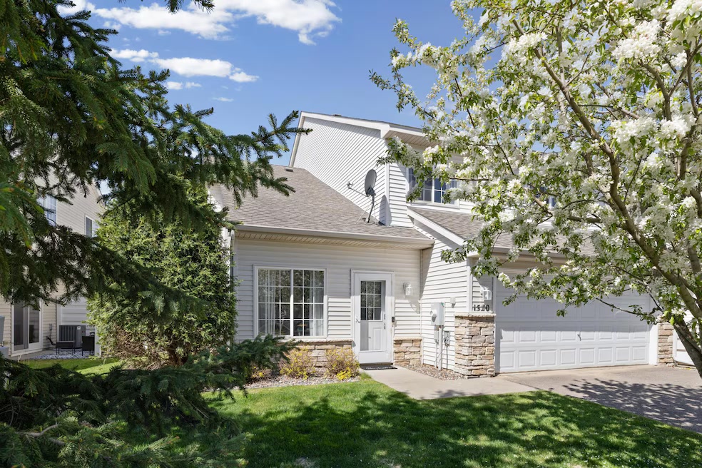 A white townhouse at 1520 Serenity Lane, Waconia, with a blossoming tree in the front yard